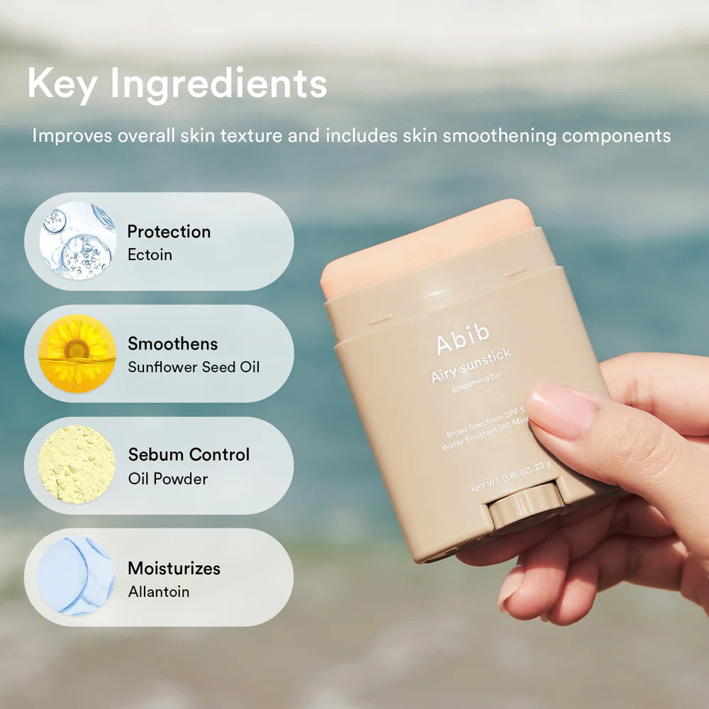 Hand holding a beige stick with 'Abib' branding, featuring key ingredients on a blurred natural background.