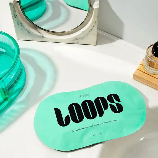 A green LOOPS sheet mask laid on a surface with a reflection in the background.