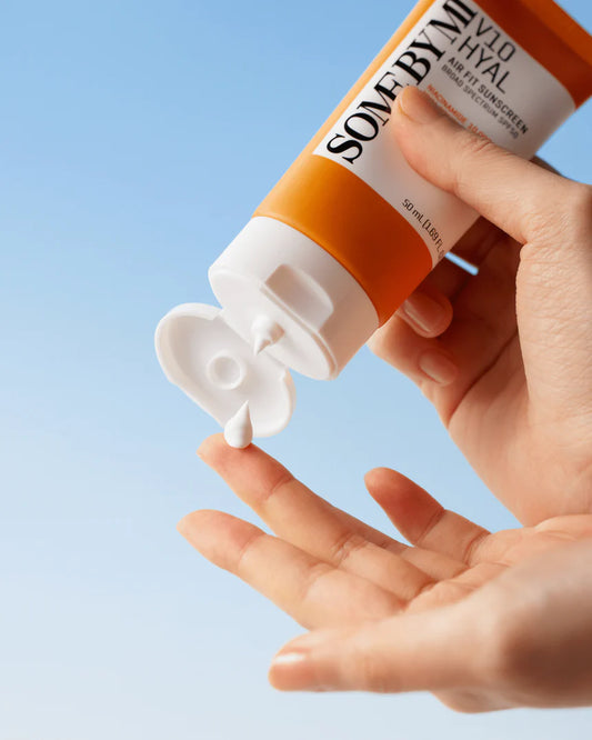 A person is applying somebymi sunscreen lotion to their hand, which is partially covered by the sunscreen. somebymi v10 hyal airfit sunscreen